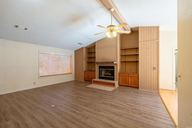 unfurnished living room featuring visible vents, wood finished floors, beamed ceiling, built in shelves, and a fireplace