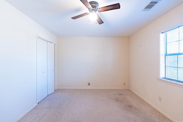 unfurnished bedroom with baseboards, visible vents, a ceiling fan, light colored carpet, and a closet