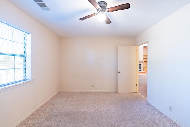 spare room with visible vents, baseboards, a ceiling fan, and light colored carpet