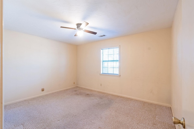 unfurnished room featuring light carpet, visible vents, a ceiling fan, and baseboards