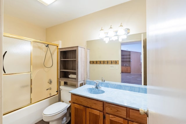 bathroom with enclosed tub / shower combo, vanity, and toilet