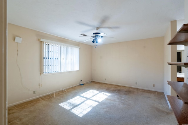 empty room featuring a ceiling fan, light colored carpet, visible vents, and baseboards