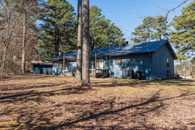 rear view of house featuring metal roof and a yard