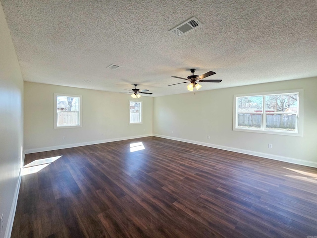 spare room featuring baseboards, visible vents, and dark wood finished floors