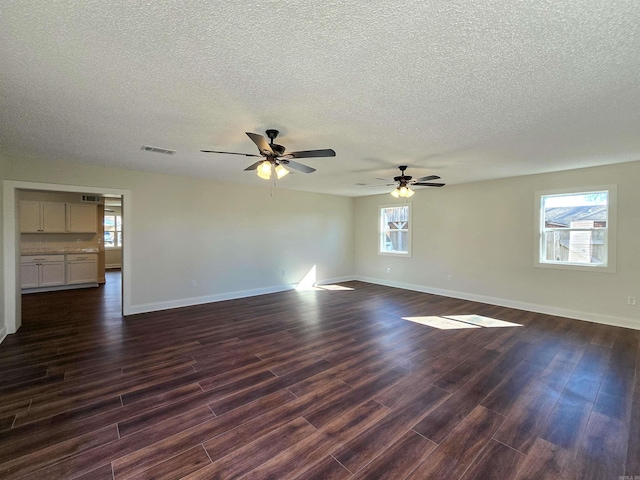 unfurnished room with baseboards, visible vents, dark wood finished floors, and a textured ceiling