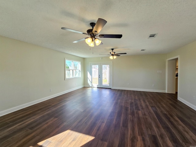 unfurnished room featuring baseboards, visible vents, dark wood finished floors, a textured ceiling, and french doors