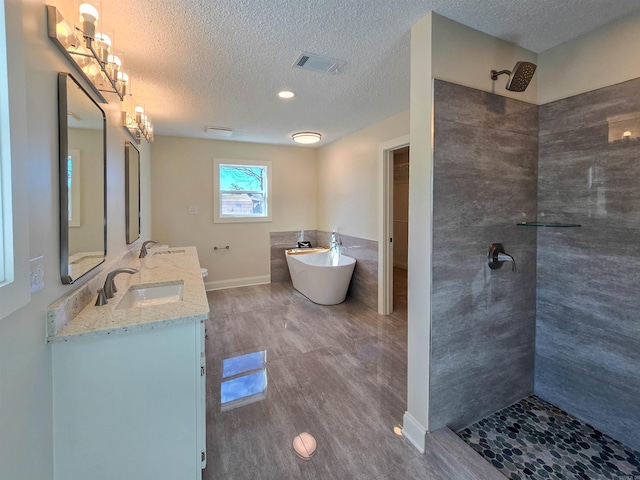 bathroom featuring a tile shower, double vanity, a freestanding tub, and a sink