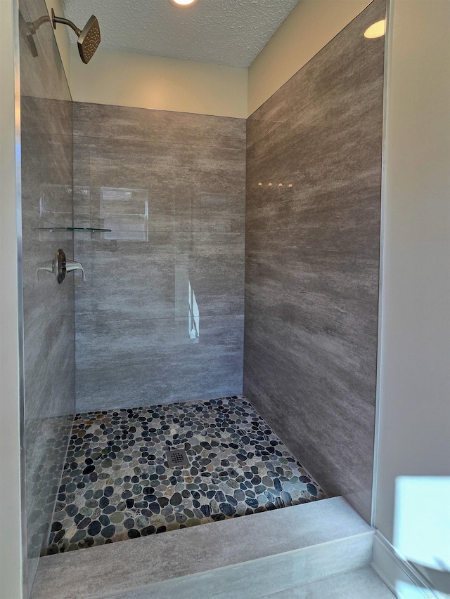 full bathroom featuring a tile shower and a textured ceiling