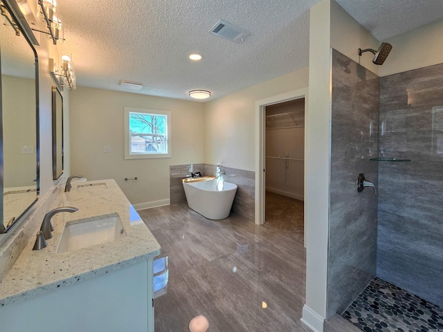 full bathroom with double vanity, visible vents, tiled shower, a soaking tub, and a sink