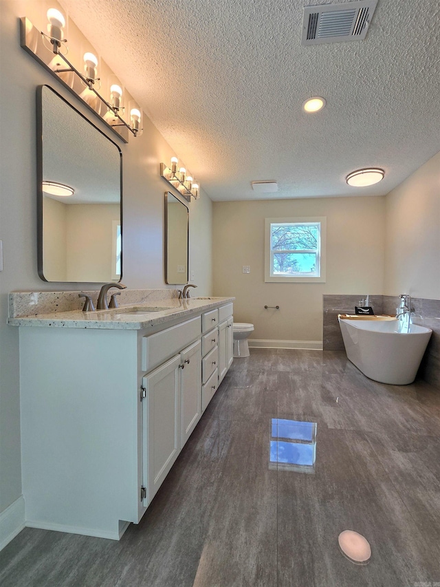 full bathroom featuring double vanity, visible vents, a sink, and wood finished floors