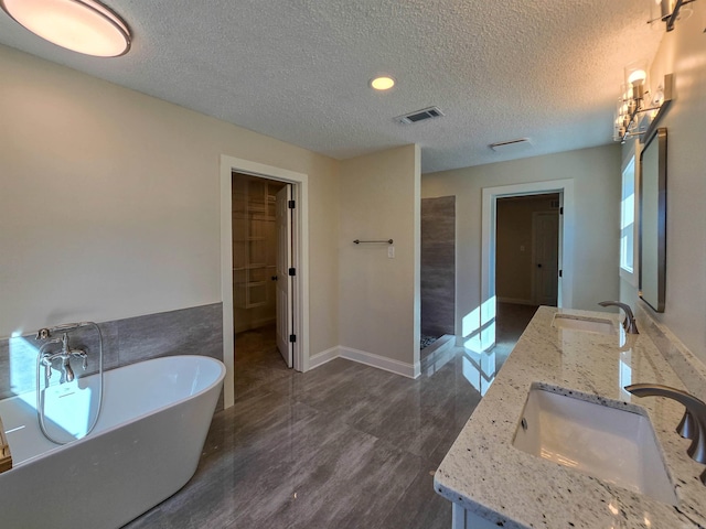 full bath featuring a freestanding tub, visible vents, a sink, and double vanity