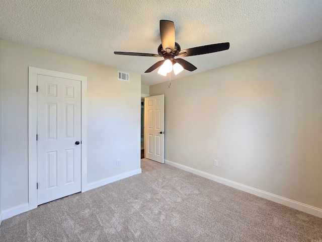 unfurnished bedroom featuring a textured ceiling, carpet floors, visible vents, and baseboards