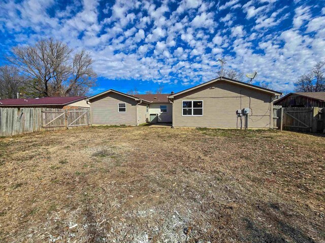 rear view of property featuring fence and a gate