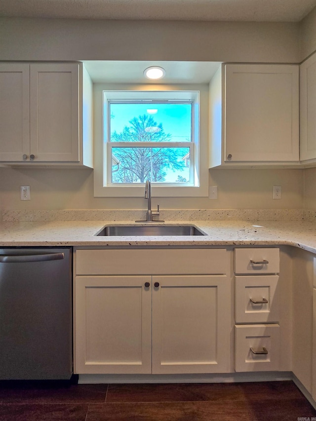 kitchen with stainless steel dishwasher, a sink, and white cabinetry