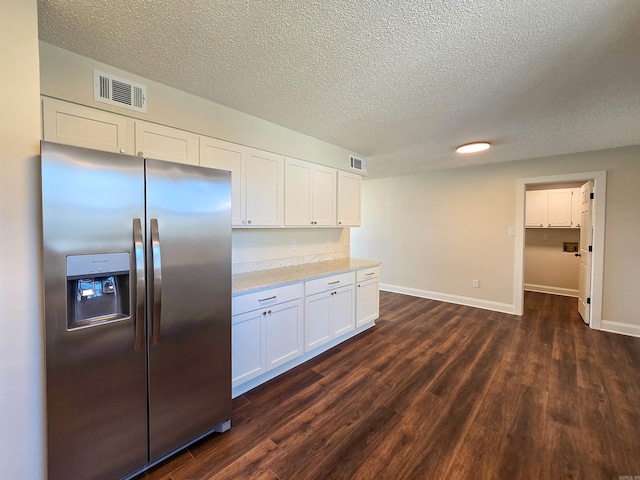 kitchen featuring dark wood-style floors, white cabinetry, visible vents, and stainless steel refrigerator with ice dispenser