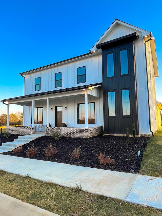 view of front of house with covered porch, board and batten siding, and brick siding