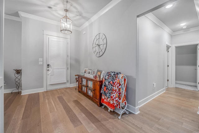 foyer entrance featuring baseboards, ornamental molding, a chandelier, and wood finished floors