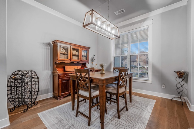 dining area with light wood finished floors, visible vents, and baseboards