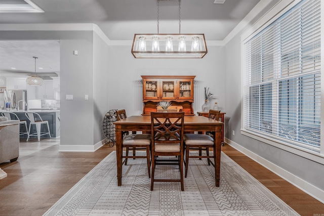 dining room with light wood-style floors, baseboards, and crown molding