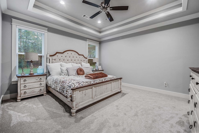 bedroom featuring a raised ceiling, visible vents, light carpet, multiple windows, and baseboards