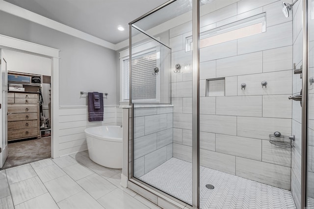 full bathroom featuring a stall shower, a spacious closet, a freestanding bath, and a wainscoted wall