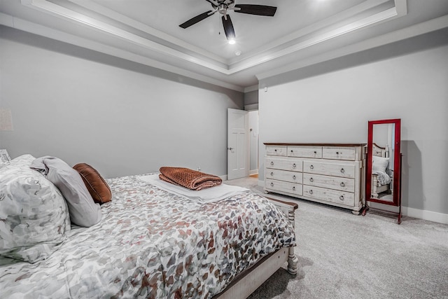 bedroom featuring baseboards, a ceiling fan, a tray ceiling, crown molding, and carpet floors