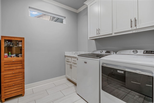 laundry area featuring crown molding, separate washer and dryer, cabinet space, and baseboards