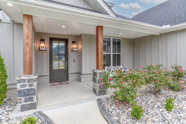 property entrance with board and batten siding, covered porch, and roof with shingles