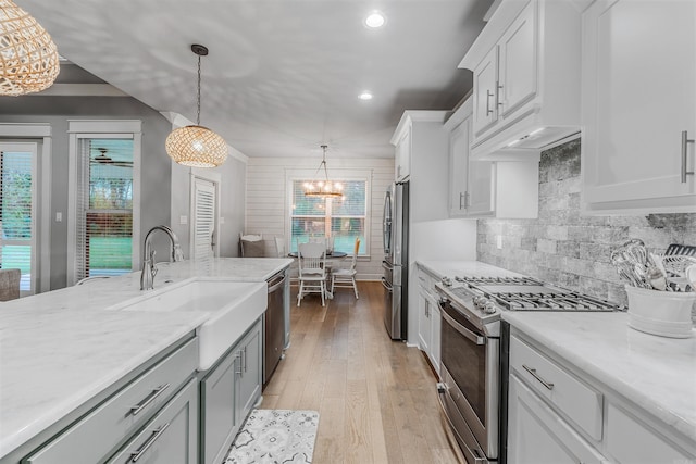 kitchen featuring backsplash, stainless steel appliances, light wood-type flooring, white cabinetry, and a sink