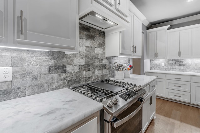 kitchen with stainless steel gas stove, dark wood finished floors, white cabinets, decorative backsplash, and premium range hood