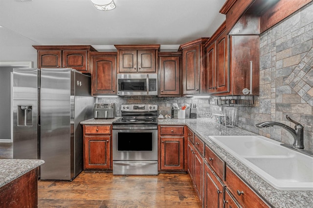 kitchen with dark wood-type flooring, appliances with stainless steel finishes, backsplash, and a sink