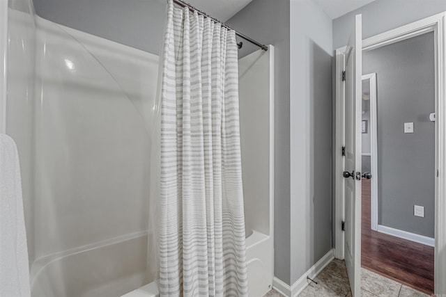 bathroom with shower / tub combo, baseboards, and tile patterned floors