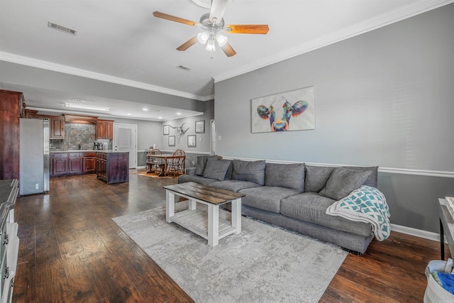 living room with ornamental molding, dark wood-style flooring, visible vents, and baseboards