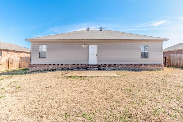 rear view of property featuring entry steps, a patio area, a fenced backyard, and a lawn