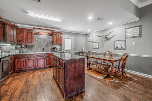 kitchen with tasteful backsplash, dark wood-style floors, stainless steel electric range oven, a center island, and crown molding