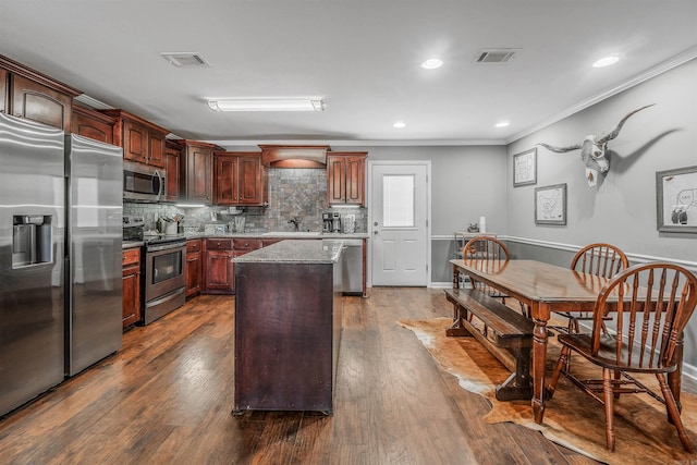 kitchen with stainless steel appliances, dark wood-style flooring, crown molding, and a kitchen island