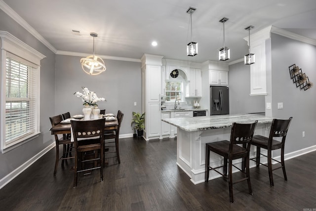 kitchen with light stone counters, a breakfast bar, dark wood-type flooring, fridge with ice dispenser, and a sink