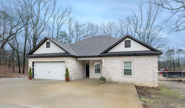 view of front of house with a garage, a shingled roof, concrete driveway, and brick siding