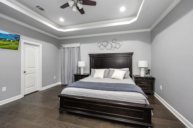 bedroom featuring a tray ceiling, wood finished floors, visible vents, and baseboards