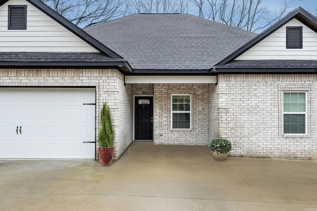 view of front of home featuring a shingled roof, an attached garage, and brick siding