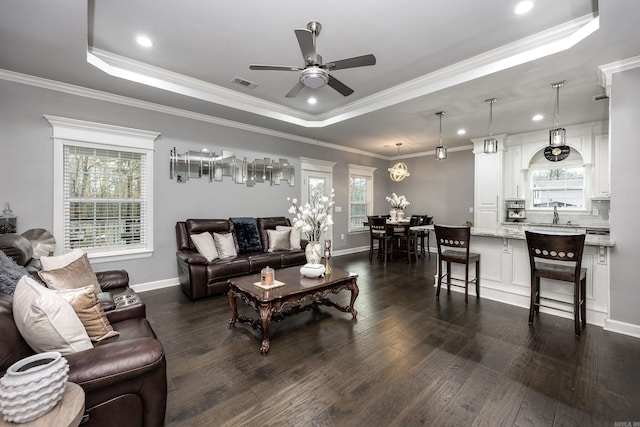 living area featuring a tray ceiling, visible vents, and plenty of natural light