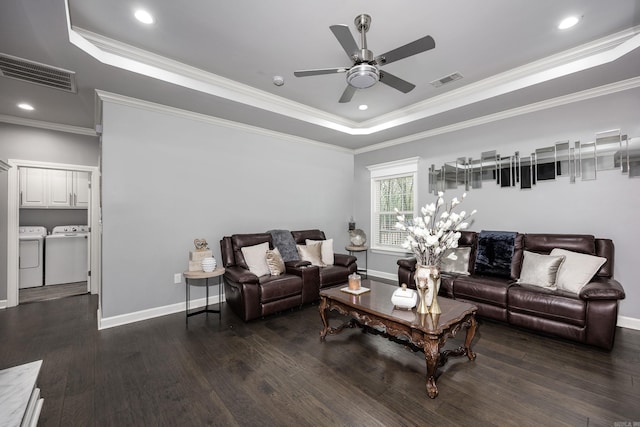 living area with visible vents, a raised ceiling, wood finished floors, and independent washer and dryer