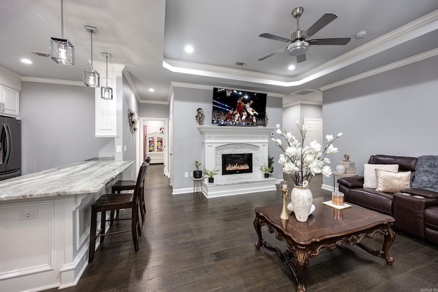 living room with dark wood finished floors, recessed lighting, a raised ceiling, visible vents, and a glass covered fireplace