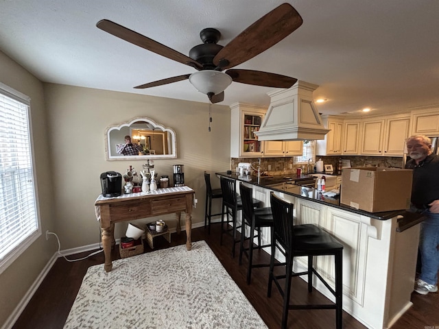 kitchen with tasteful backsplash, baseboards, dark wood-type flooring, and a kitchen breakfast bar