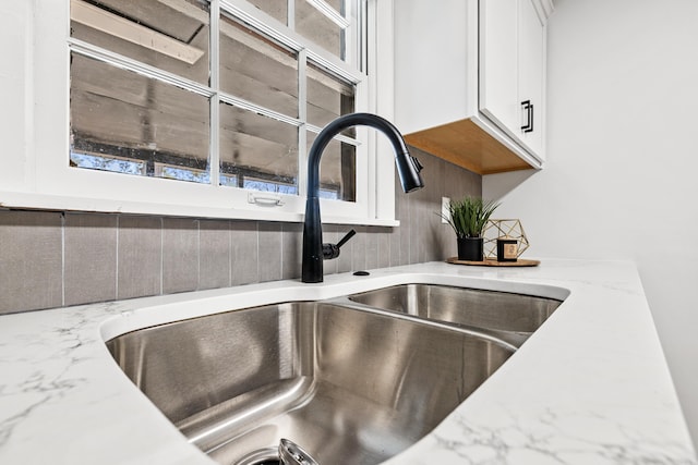 room details with light stone counters, white cabinets, and a sink