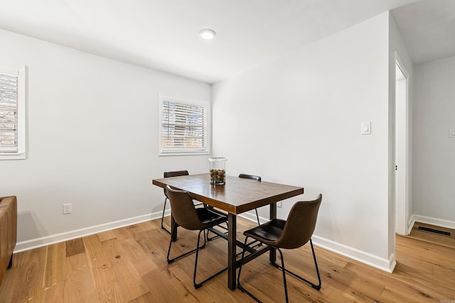 dining room with light wood-style floors, visible vents, and baseboards