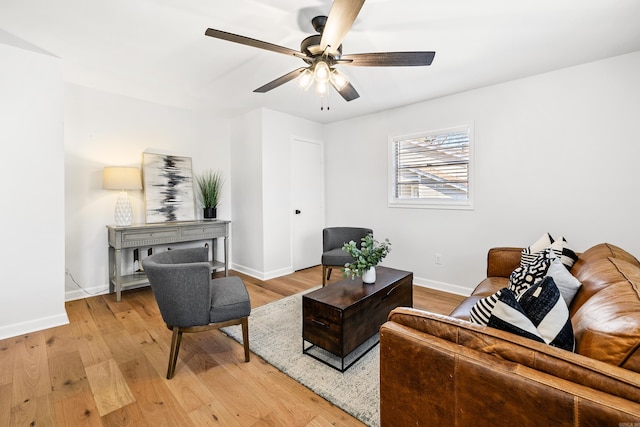 living area featuring a ceiling fan, light wood-type flooring, and baseboards