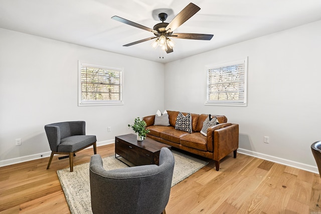 living area featuring light wood finished floors, baseboards, and a ceiling fan