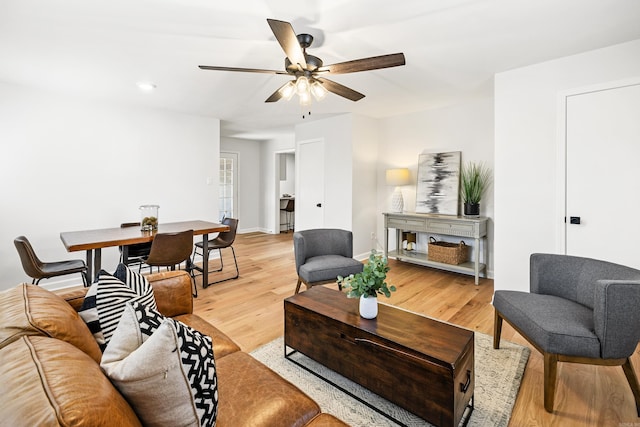 living room featuring ceiling fan, light wood-type flooring, and baseboards