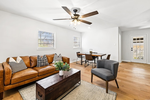 living room featuring a ceiling fan, light wood-style flooring, and baseboards